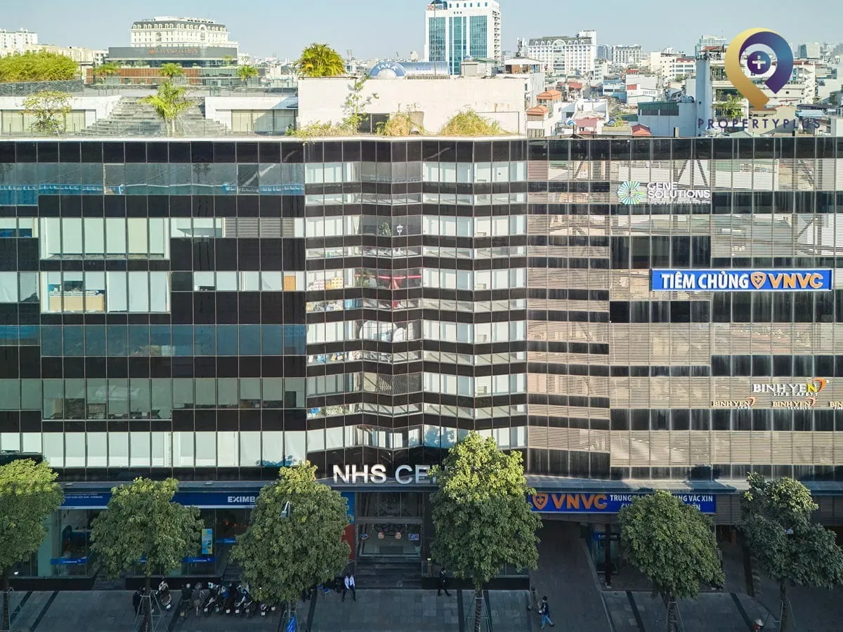 Toàn cảnh tòa nhà NHS Center nhìn từ phía trước, nổi bật với mặt kính hiện đại.